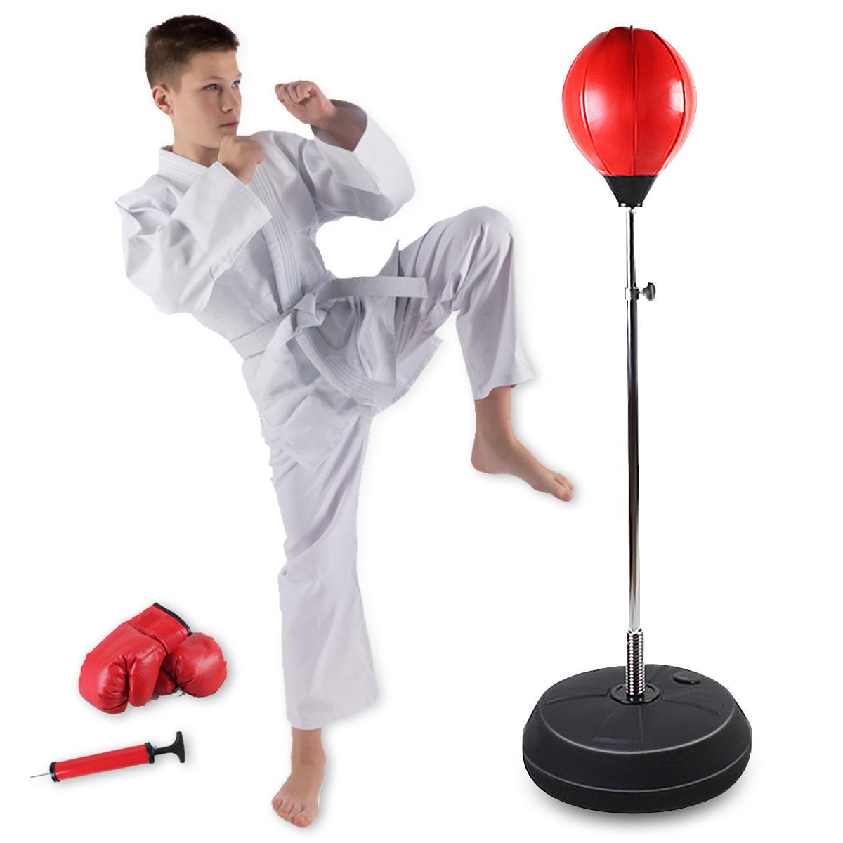 young boy wearing karate outfit kicking free standing red punching bag with black base